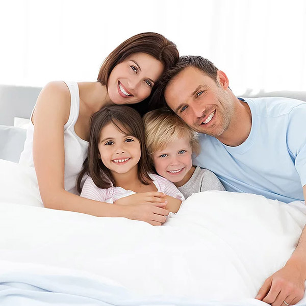 young family under covers in bed